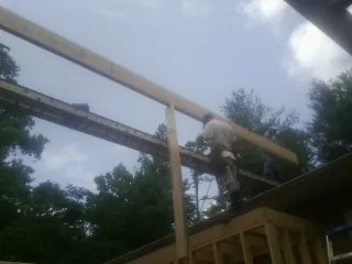 Carpenter setting a ridge beam over a new addition frame — Ice Dam Removal by Roofing Brothers in Davilla
