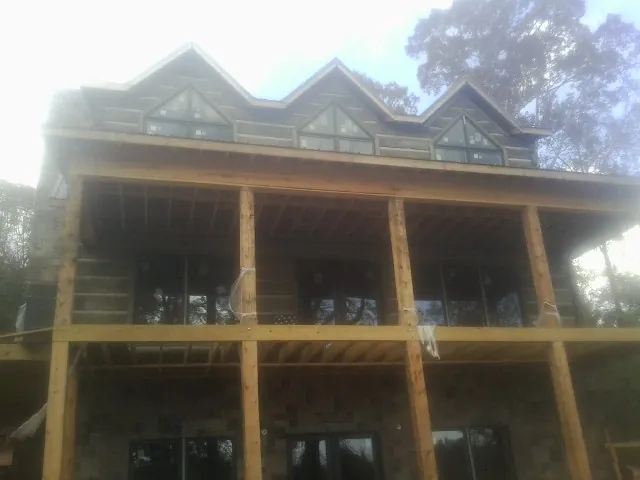 Dormers and porch framing on a large log home under construction — Roof Coating work by our crew in Davilla