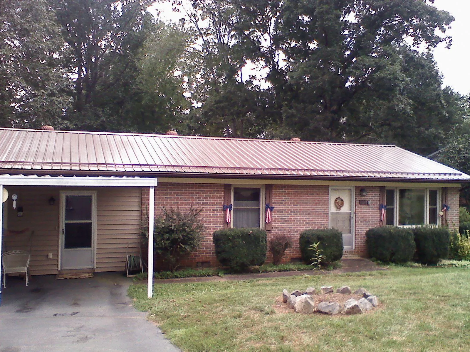 Bronze metal roof and carport on a brick ranch home — Roof Repair work by our crew in Davilla